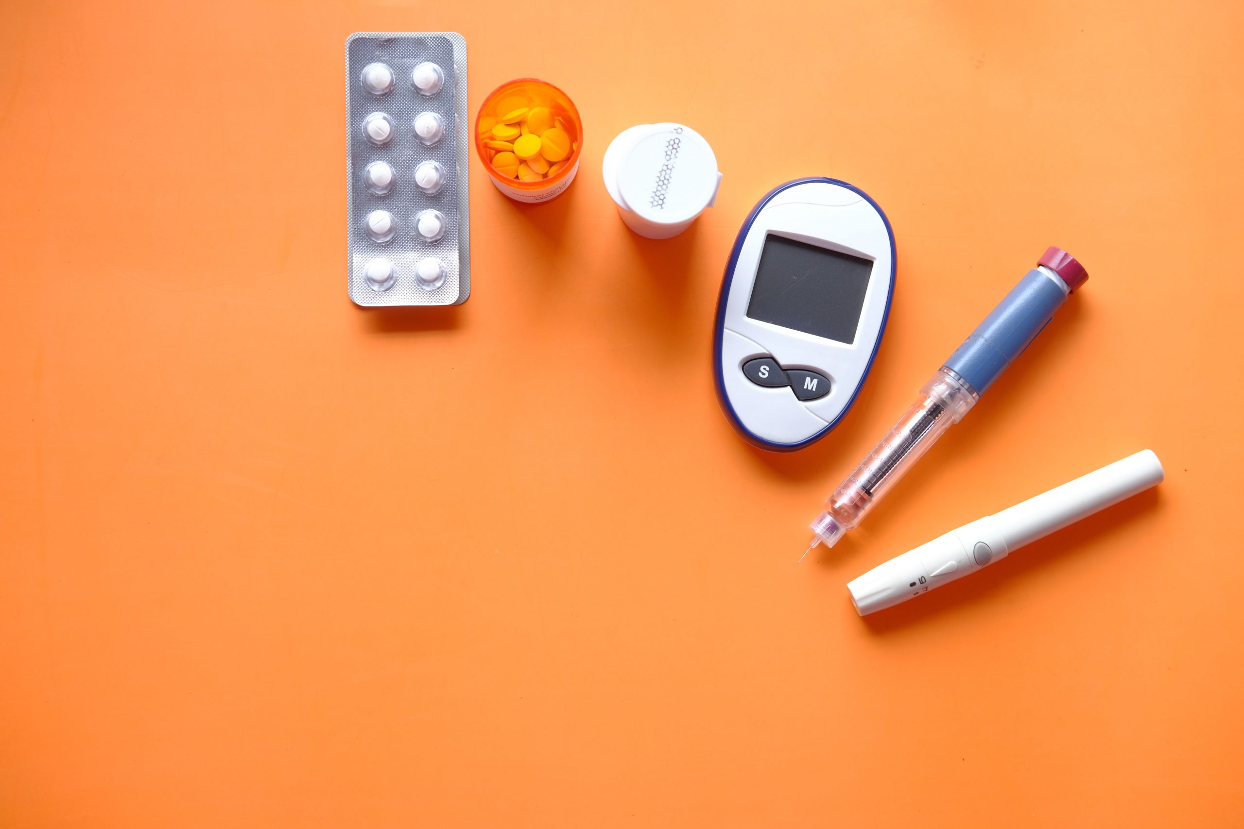 Insulinpräparate und Blutzuckermessgerät von Orangem Hintergrund.